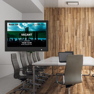 Qbic 10.1-inch Smart Panel PC mounted in a conference room, displaying real-time scheduling on screen